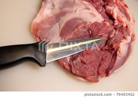 Boning a shoulder of lamb leg meat on a wooden tray, white background, Top view Boning a shoulder of lamb leg meat on a wooden tray, white background, Top view 76483482