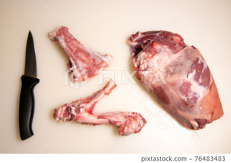 Boning a shoulder of lamb leg meat on a wooden tray, white background, Top view Boning a shoulder of lamb leg meat on a wooden tray, white background, Top view 76483483