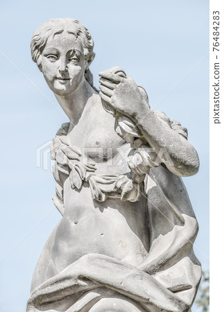 Ancient statue covered with moss and lichen of a sensual renaissance era woman in Potsdam, Germany 76484283
