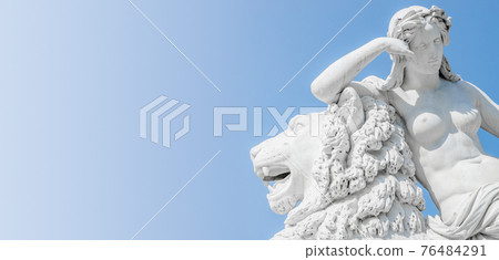 Banner of an ancient statue sensual Renaissance Era woman laying on big lion with blue sky gradient background in Potsdam, Germany, details, closeup 76484291
