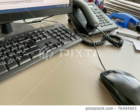 Black modern computer mouse keyboard and telephone on a working office table in a business company 76484803