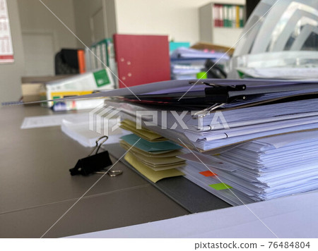 Large thick folders with important papers and documents on a working office desk with stationery and accessories Large thick folders with important papers and documents on a working office desk with stationery and accessories 76484804
