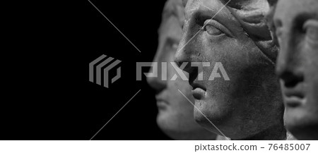 Marble ancient different heads as humankind in a isolated black background, streamer, banner with paste space 76485007