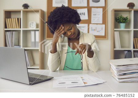 Tired african american businesswoman suffering from headache sit at office table Tired african american businesswoman suffering from headache sit at office table 76485152