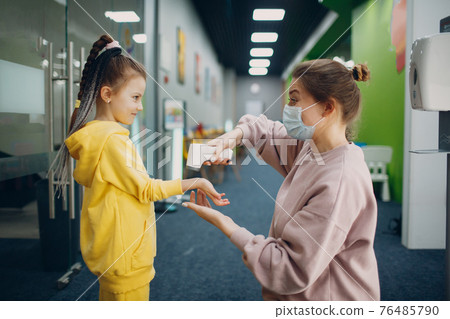 Child hand temperature measurement by laser thermometer at kindergarten. 76485790