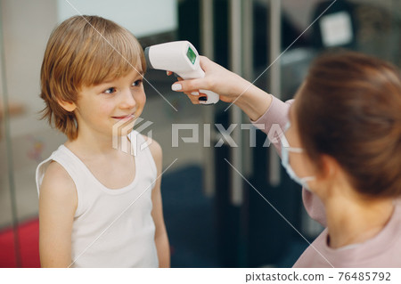 Child temperature measurement by laser thermometer at kindergarten. 76485792