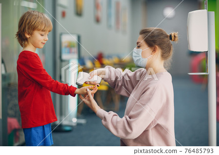 Child temperature measurement by laser thermometer at primary school. 76485793