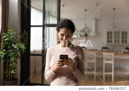 Satisfied young female buying goods at web shop using phone 76486257