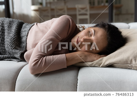 Serene millennial latin lady nap on couch enjoy comfortable rest Serene millennial latin lady nap on couch enjoy comfortable rest 76486313