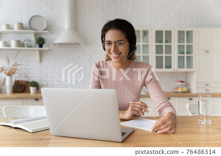 Smiling hispanic female student in earphones look on pc screen Smiling hispanic female student in earphones look on pc screen 76486314