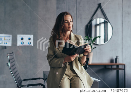 Woman entrepreneur at work reading notes in a planner 76487673