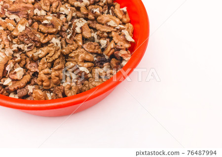 Peeled walnuts in red plastic plate on white background, isolated 76487994