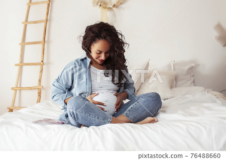 young pretty african american woman pregnant laying in bed, lifestyle people concept 76488660