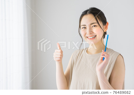 Young woman doing a good mark while holding a toothbrush Young woman doing a good mark while holding a toothbrush 76489082