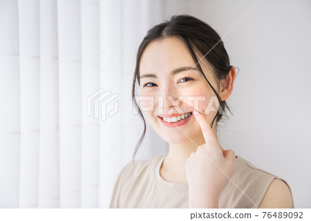 指著她的牙齒的年輕女子 76489092