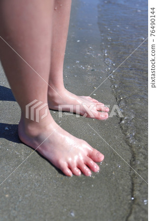 Bare feet at the water's edge 76490144
