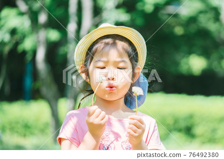 Girls blowing dandelion's fluff 76492380