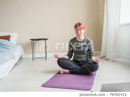 Front view to young woman meditate in bedroom Front view to young woman meditate in bedroom 76492412