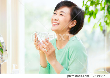 A woman holding a glass of water 76493349