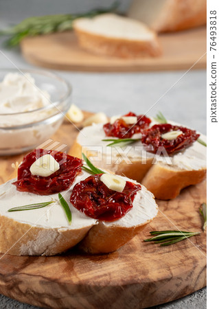 Homemade sandwiches with cream cheese and sun-dried tomatoes on a wooden board of olive - delicious healthy breakfast, vertical image, copy space 76493818
