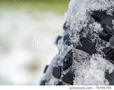 Detail of snow and ice imprinted in a thick winter tire tread on a fatbike. 76496794
