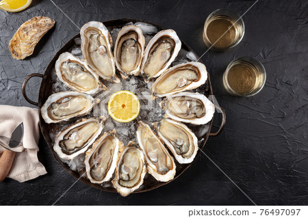 Oysters. A dozen of raw oysters with wine and lemons, overhead flat lay shot Oysters. A dozen of raw oysters with wine and lemons, overhead flat lay shot 76497097
