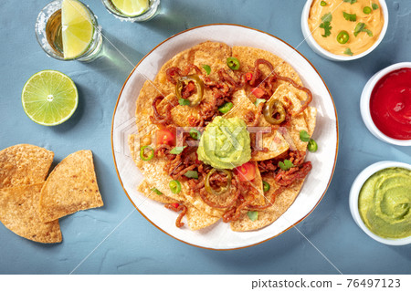 Mexican nachos, shot from above with a variety of dips and sauces Mexican nachos, shot from above with a variety of dips and sauces 76497123