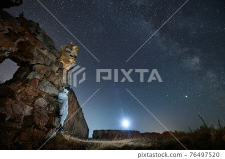 Spaceman enjoying beautiful view starry sky. 76497520