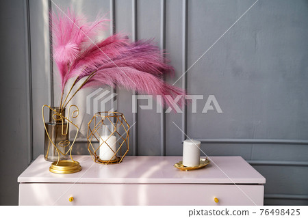 light pink dresser at the gray wall decorated with candles and colored feathers. light pink dresser at the gray wall decorated with candles and colored feathers. 76498425