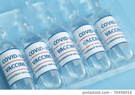 Vaccine against COVID-19. Glass medical vials with liquid. Ampoules with coronavirus vaccine on a medical glass table 76498918
