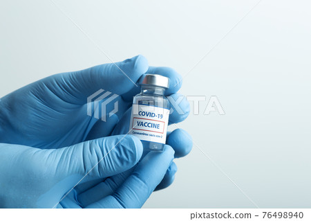Vaccine against COVID-19. Glass medical vials with liquid. Ampoules with coronavirus vaccine on a medical glass table 76498940