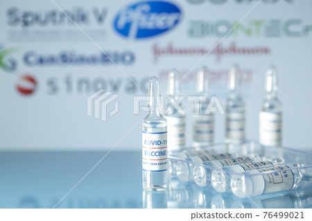 Vaccine manufacturing companies against COVID-19. Glass medical vials with liquid on the background company logos. Ampoules with coronavirus vaccine on a medical glass table. Vaccine manufacturing companies against COVID-19. Glass medical vials with liquid on the background company logos. Ampoules with coronavirus vaccine on a medical glass table. 76499021