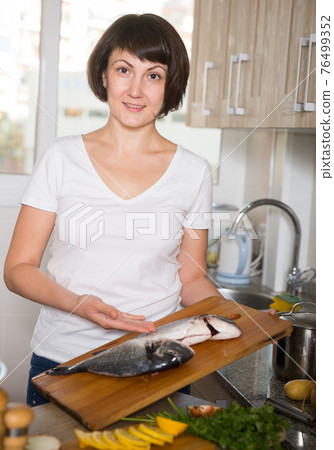 Housewife cooking dorado on cutting board 76499352