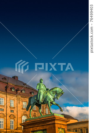 Christiansborg Palace and statue of Christian IX on horse illuminated by sunrise in early morning, Copenhagen, Denmark, summer time, paste space Christiansborg Palace and statue of Christian IX on horse illuminated by sunrise in early morning, Copenhagen, Denmark, summer time, paste space 76499403