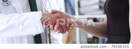 Doctor shake hand as hello with patient in office closeup 76500105