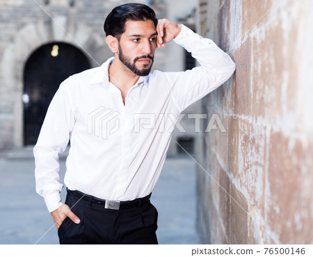 Thoughtful man leaning elbow on wall Thoughtful man leaning elbow on wall 76500146