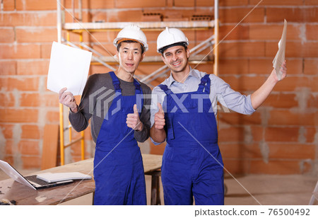 Builders holding papers with plan Builders holding papers with plan 76500492