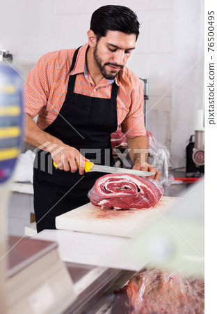 Man butcher is cutting meat on his workplace in the market. 76500495