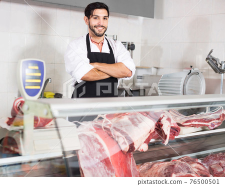 Portrait of man butcher who is posing with meat in the market. Portrait of man butcher who is posing with meat in the market. 76500501