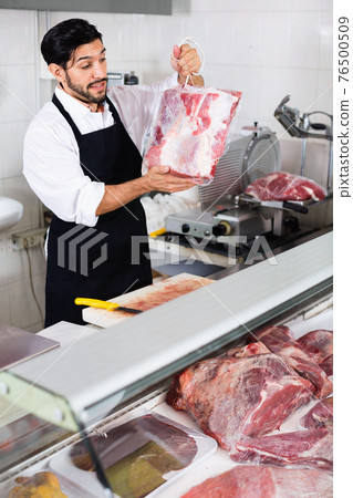 Man butcher is demonstraiting meat in the market. Man butcher is demonstraiting meat in the market. 76500509