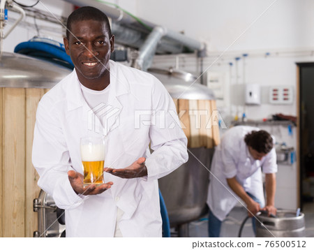 African american man brewer is standing with glass of beer African american man brewer is standing with glass of beer 76500512