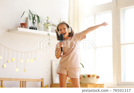 Cute little girl with hairbrush as mic pretending to be famous singer Cute little girl with hairbrush as mic pretending to be famous singer 76501317