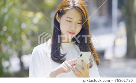 操作智能手機的婦女戶外 操作智能手機的婦女戶外 76501750