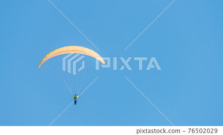 Beautiful paraglider flying in blue sky with copy space for text and smooth background, wide angle Beautiful paraglider flying in blue sky with copy space for text and smooth background, wide angle 76502029