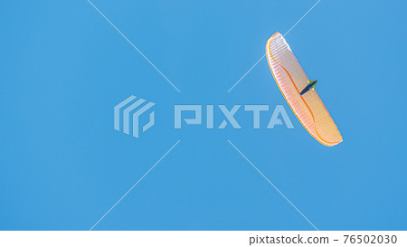 Beautiful paraglider flying in blue sky with copy space for text and smooth background, wide angle Beautiful paraglider flying in blue sky with copy space for text and smooth background, wide angle 76502030
