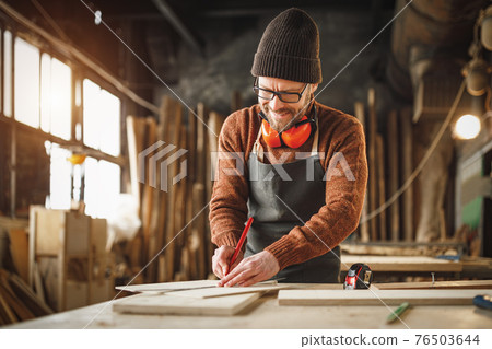 Joiner working with wooden detail in workshop 76503644