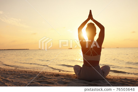 Calm woman meditating on beach at sunset 76503648