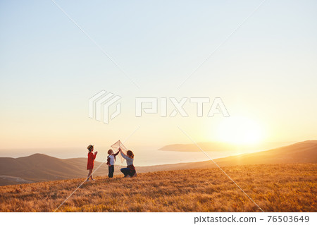 Happy family  mother and kids  launch  kite on nature at sunset 76503649