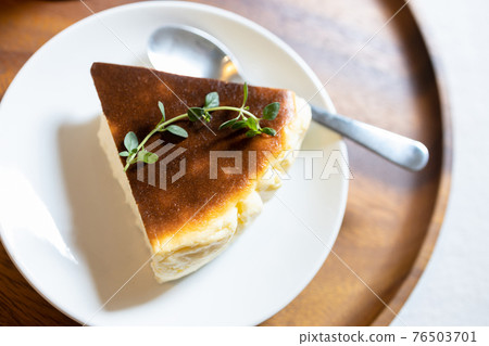 Delicious Basque Burnt Cheesecake,Tarta de Queso or San Sebastian Cheesecake cut one piece on a white ceramic plate with a spoon is placed on wooden tray,dessert cake made with cream and soft cheese Delicious Basque Burnt Cheesecake,Tarta de Queso or San Sebastian Cheesecake cut one piece on a white ceramic plate with a spoon is placed on wooden tray,dessert cake made with cream and soft cheese 76503701