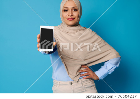 Soft focus on mobile phone in Arab Muslim woman's hands Soft focus on mobile phone in Arab Muslim woman's hands 76504217